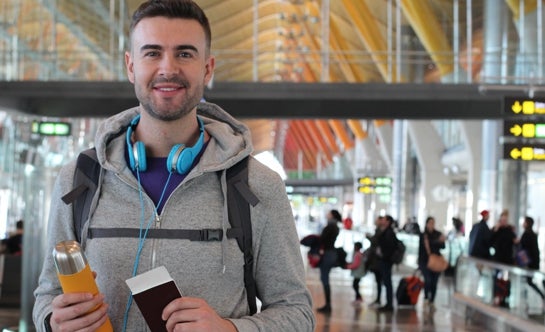 Student smiling holding water bottle and passport