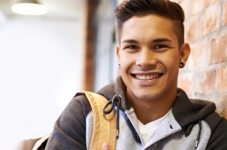 Student smiling leaning against brick wall