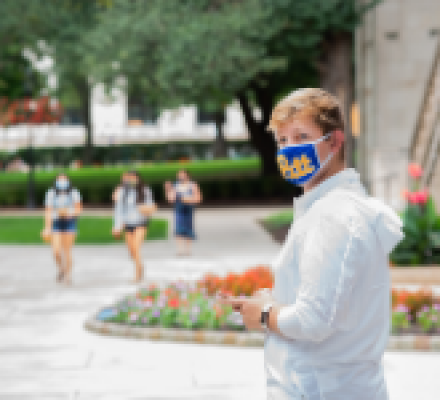 Pitt student walking outside of the Cathedral of Learning