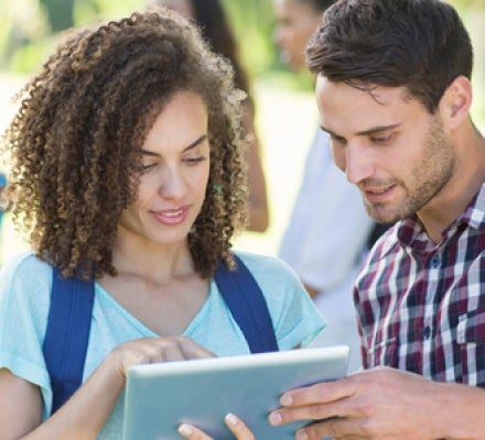 Students looking at tablet outside