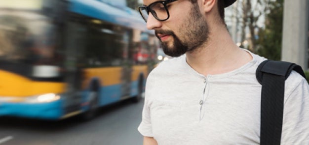 Man looking down at phone with bus in the background