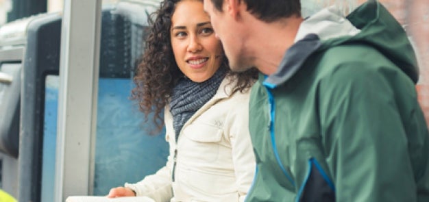 Students sitting at bus stop with open book