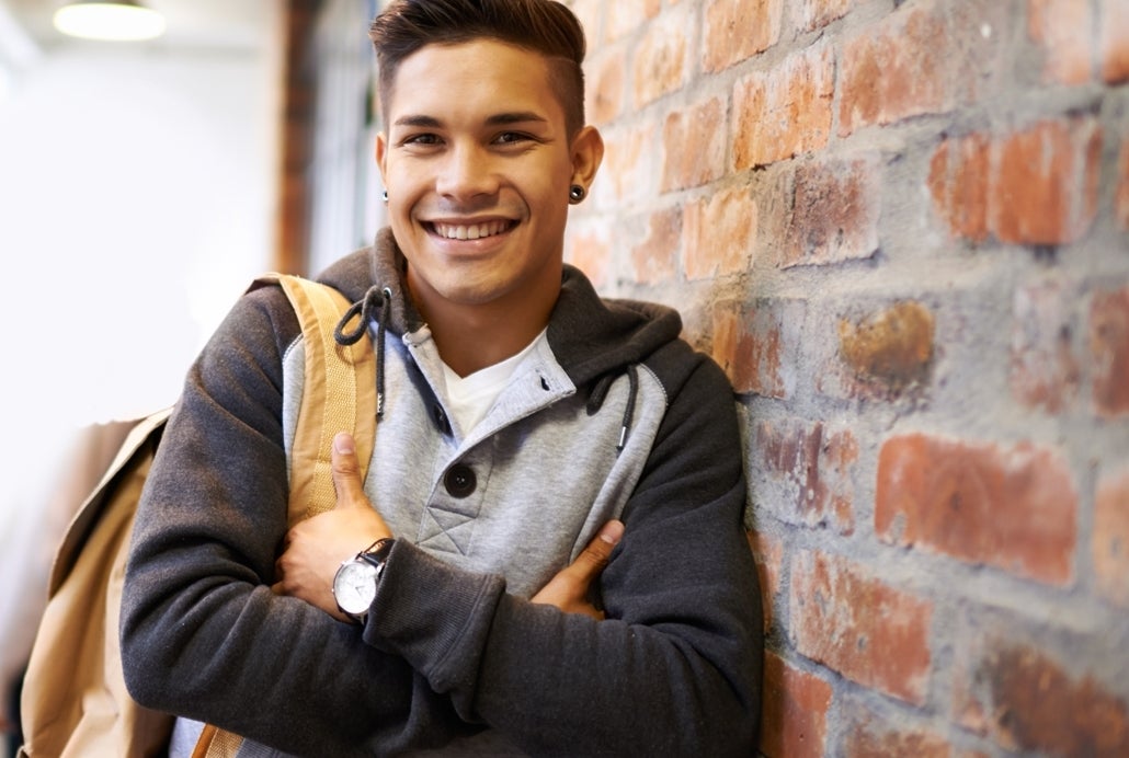 Student with backpack leaning against wall