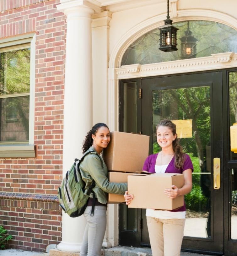 students carrying boxes outside of dorm